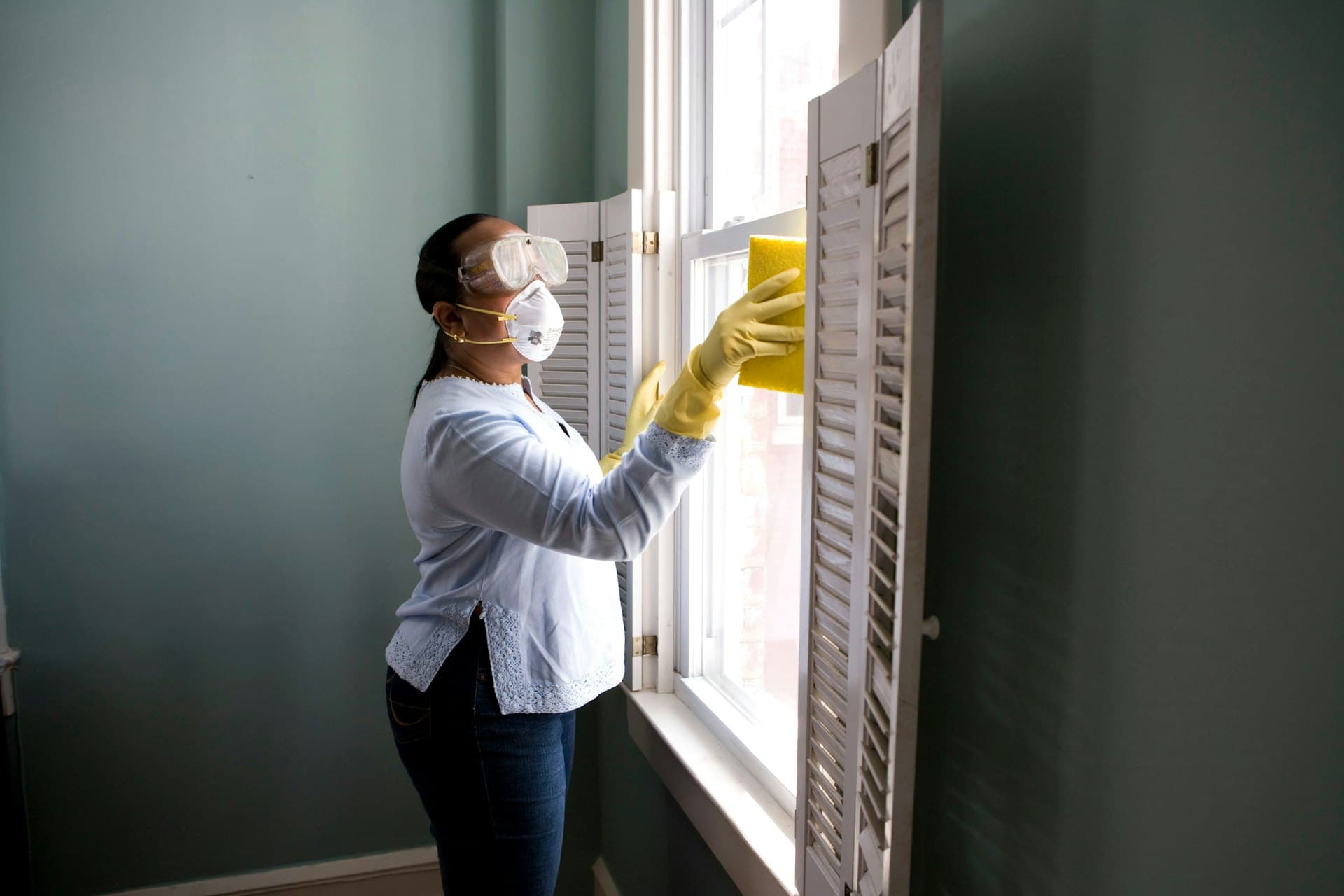 A cleaner wiping a window in a home