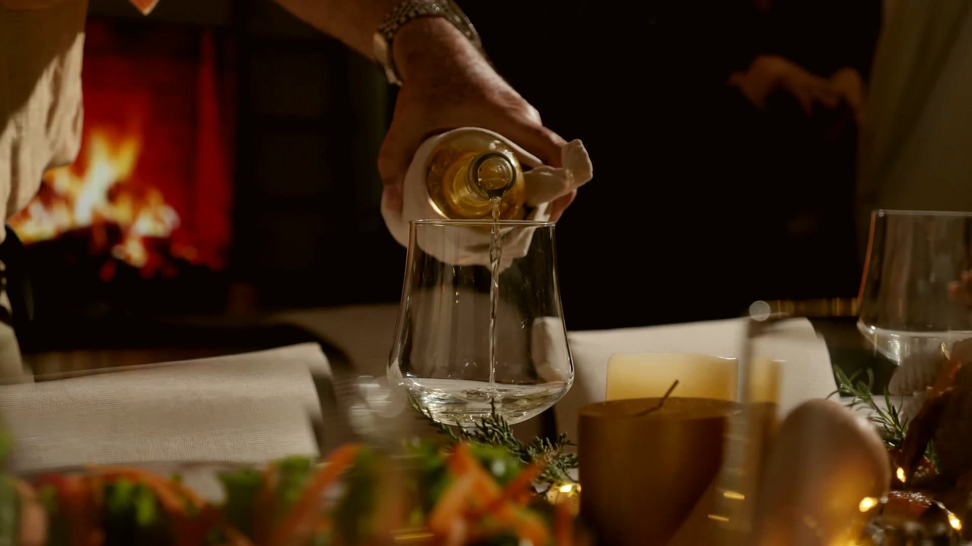 Wine poured at a candlelit table beside a fireplace